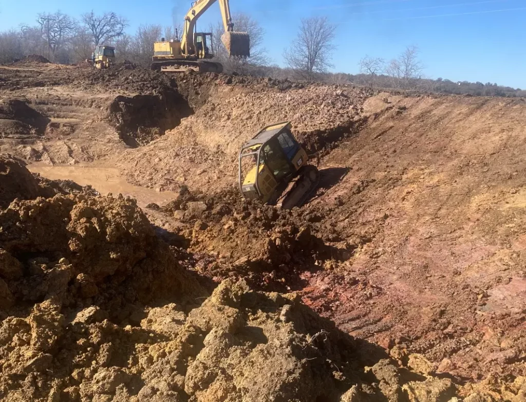 Cat D4k bulldozer digging Texas sized stock tank